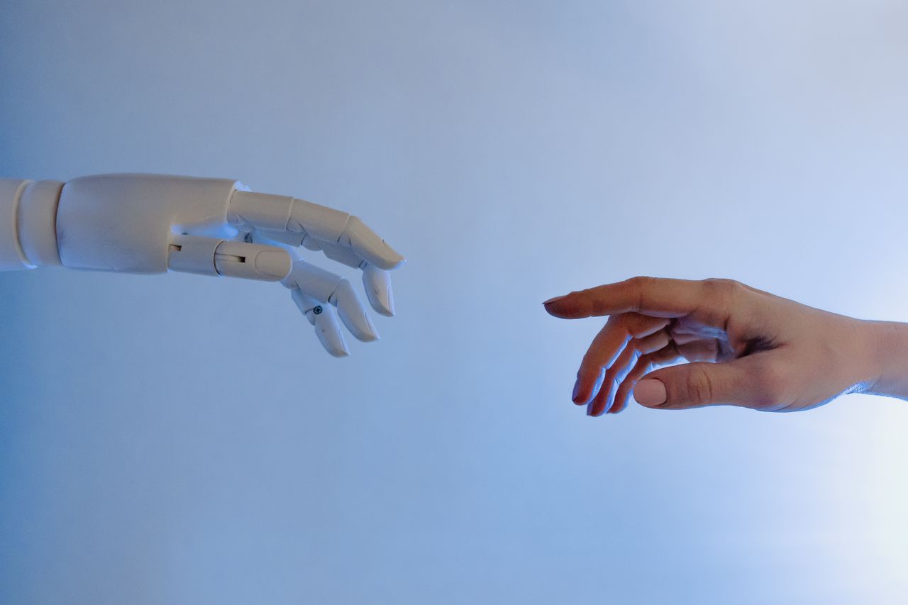 who-we-are A human hand reaching towards a robotic hand symbolizing technology and connection.